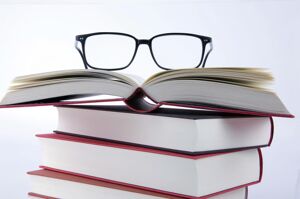 A stack of books with reading glasses